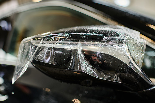 object photo of transparent protective foil applied on side view mirror of black modern car