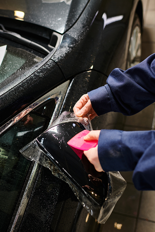 cropped view of hard working professional worker applying transparent protective foil on black car