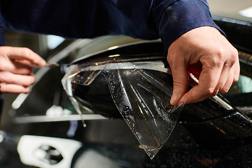 cropped view devoted hard working professional applying new protective foil on black car mirror