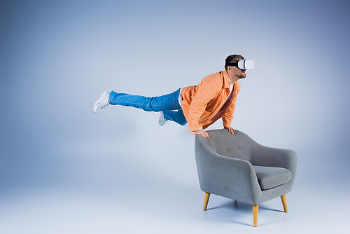 A man in an orange shirt executes a mesmerizing trick on a chair in a studio setting, showcasing his magic skills.