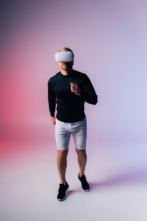 A man in a black shirt and white shorts stands confidently in a studio setting, exuding style and elegance with his outfit choice.