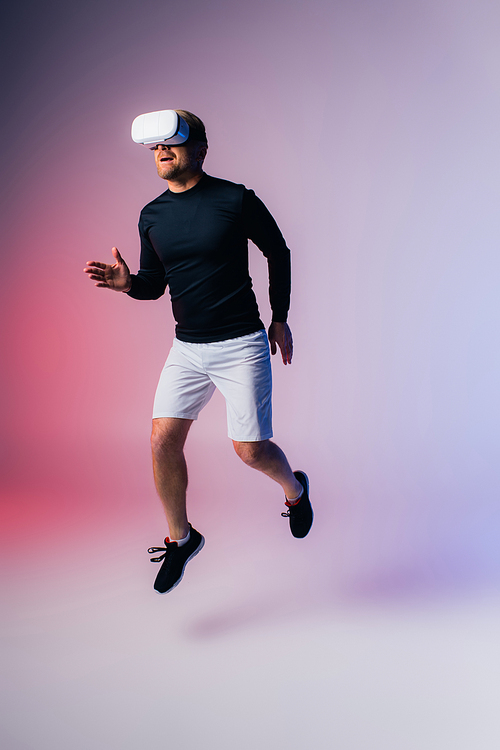 A man in black shirt and white shorts jumps gracefully in the air, exuding energy and freedom in a studio setting.