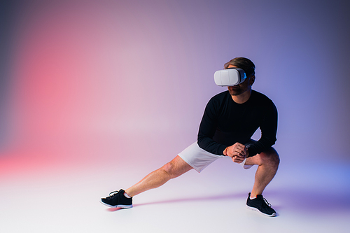 A man in a black shirt and white shorts delves into virtual reality while wearing a headset in a studio setting.