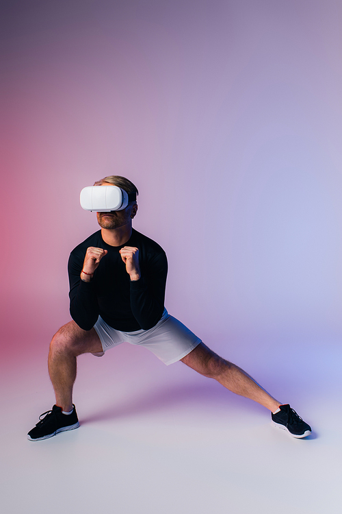 A man in a black shirt and white shorts stands confidently in a studio setting, exuding a sense of mystery and strength.