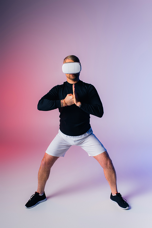 A man wearing a vr stands in front of a pink and blue background, lost in a world of imagination and dreams.