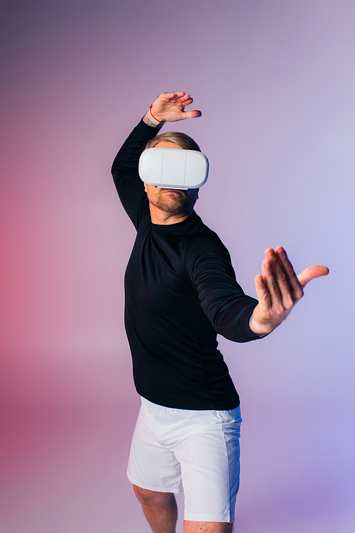 A man in a black shirt and white shorts is striking dynamic poses in a studio setting while immersed in the virtual reality world.