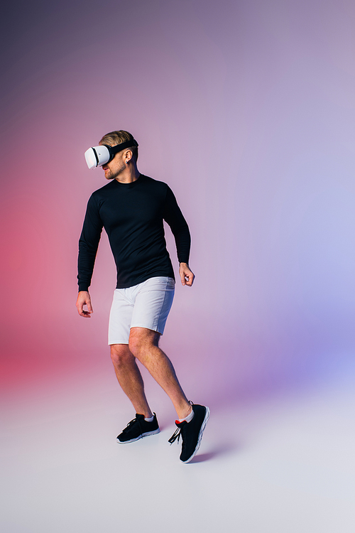 A man in a black shirt and white shorts showcases his moves in a virtual reality headset in a studio setting.