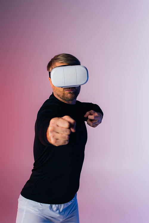 A man in a black shirt and white shorts, wearing a blindfold, stands immersed in the metaverse experience in a virtual reality studio.