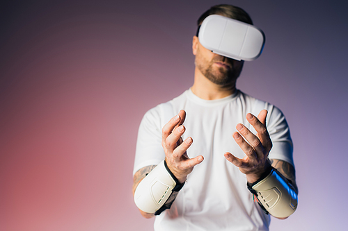 A man in a white shirt donning wrist braces in a virtual reality studio setting.