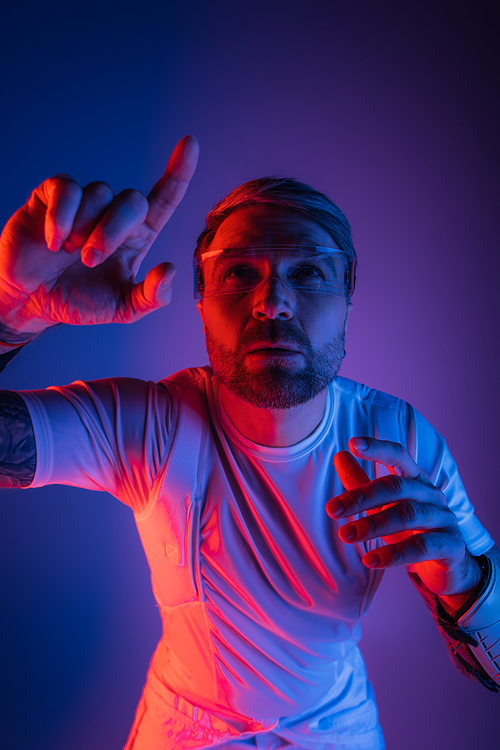 A man, dressed in a white shirt, raises his hand in a studio setting. He projects a sense of ethereal connection and presence.