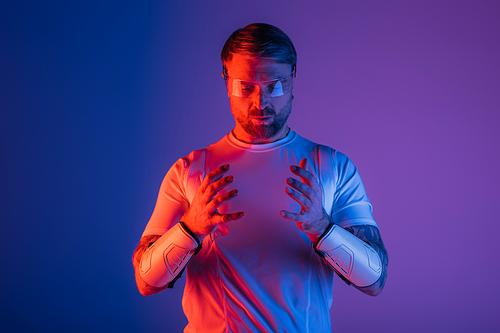 A man in a white shirt, hands intertwined, exuding calmness and poise in a studio setting with virtual reality elements.