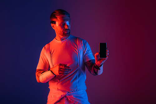 A man in smart glasses holds a cell phone, deeply engaged in the virtual reality world around him.