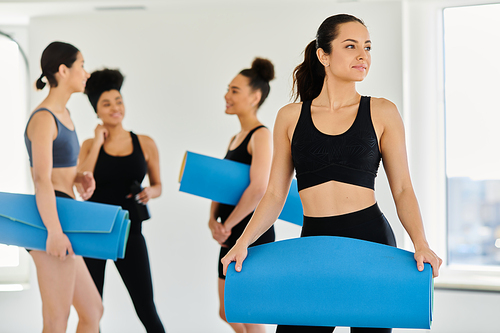 focus on brunette young woman in sportswear standing with fitness mat in pilates studio