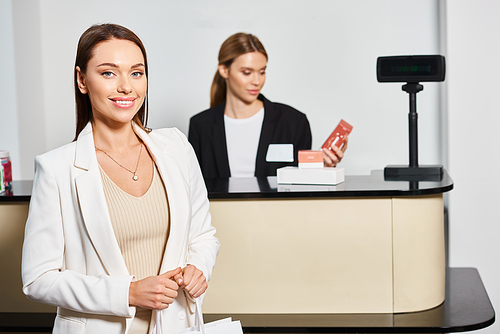 joyous beautiful female customer looking at camera next to shop assistant in cosmetics store