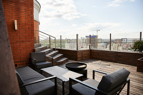 A cozy balcony setting with two chairs and a table, overlooking a bustling cityscape below