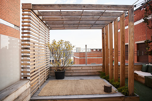 A tranquil outdoor space featuring a charming wooden pergola adorned with climbing vines and a filled planter box