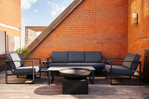 A cozy setup of a couch and chairs on a wooden deck, surrounded by nature, perfect for relaxing or entertaining outdoors