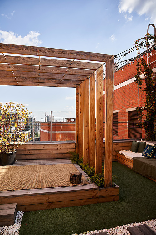 A cozy outdoor living area featuring a beautiful wooden pergola surrounded by lush greenery, inviting seating, and a tranquil ambiance