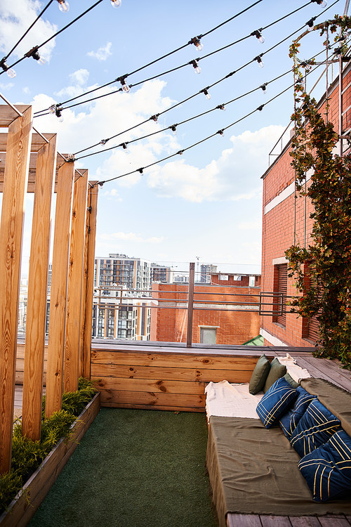 A cozy couch is set on a balcony under warm string lights, creating a dreamy and inviting atmosphere