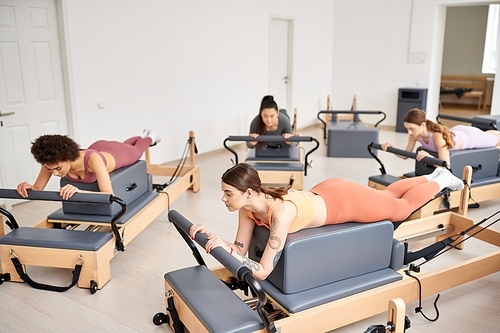 Sporty women engaging in a Pilates session in a bright room.