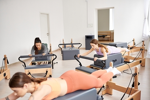 A vibrant group of sporty women engaged in a pilates session in a bright room.