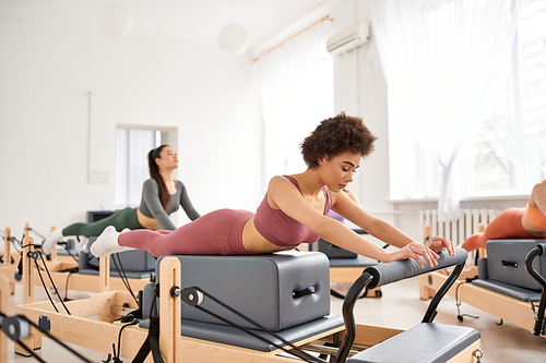 Sporty women practicing in a gym during a pilates lesson.