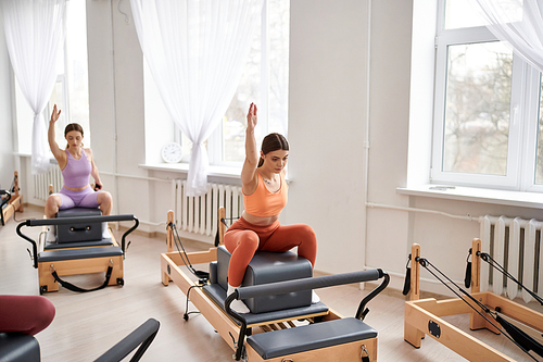 Sporty women performing dynamic exercises during a Pilates lesson.