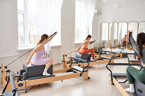 Athletic women in sportswear during pilates in a gym together.