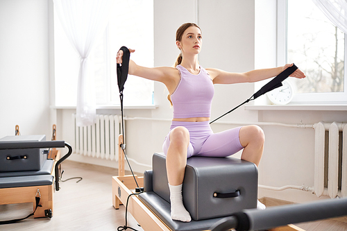 Appealing woman in sportwear exercising on pilates lesson.