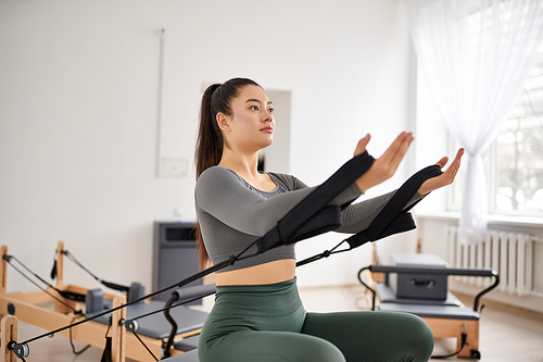 Appealing woman in cozy attire actively exercising on pilates lesson.