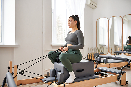 Attractive woman in cozy attire actively exercising on pilates lesson.