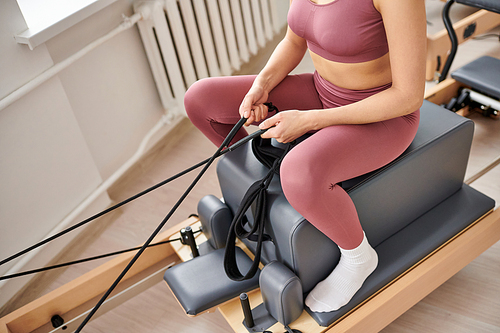 Young woman in cozy attire actively exercising on pilates lesson.