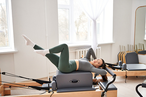 Athletic woman in cozy attire actively exercising on pilates lesson.