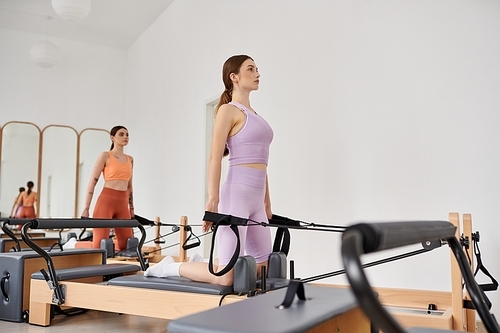 Athletic women gracefully practicing pilates in a gym together.