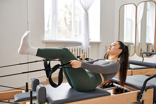 Sporty woman actively practising while on pilates lesson.