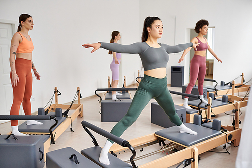 A diverse group of sporty women engaging in a dynamic pilates class full of energy and movement.