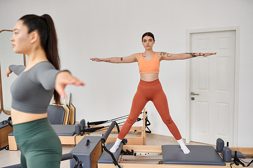 Young women gracefully practicing pilates in a gym together.