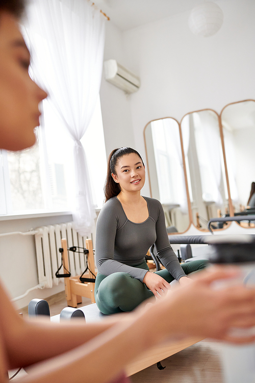 Beautiful women spending time together on pilates lesson in gym, relaxing.