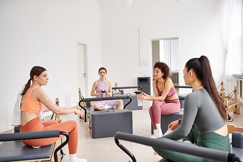 Fit women spending time together on pilates lesson in gym, relaxing.