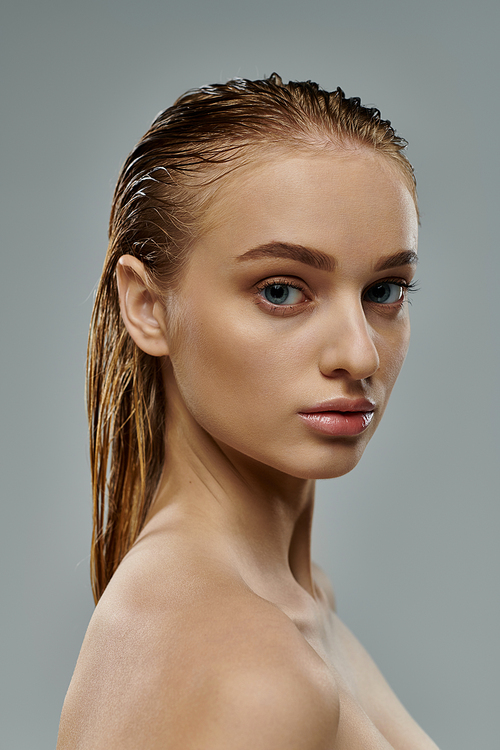 Beautiful woman posing with wet hair on gray backdrop.