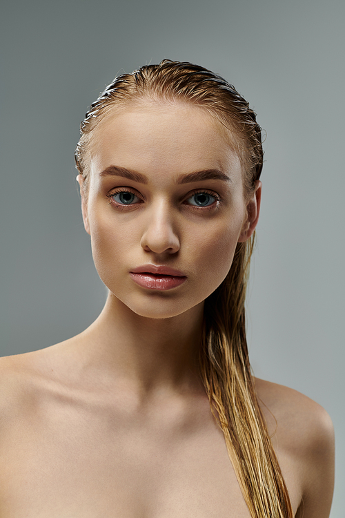 Alluring woman with long hair is gently touching her wet hair.