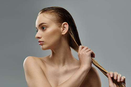 Beautiful woman with long hair is gently touching her wet hair.