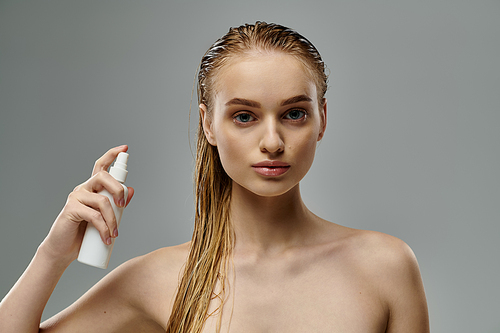 A woman gracefully holds a bottle of lotion, highlighting her hair care routine with wet hair.