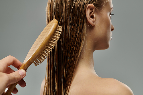 A young beautiful woman delicately brushes her wet hair.