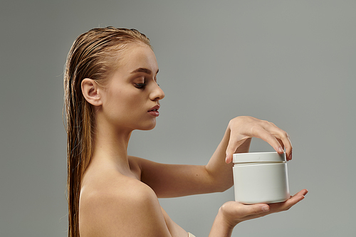 A young beautiful woman showcasing her hair care routine with wet hair, holding a container.