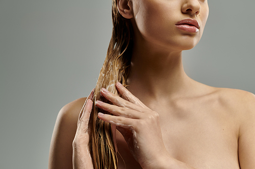 Woman with long hair tenderly applying hair care products.