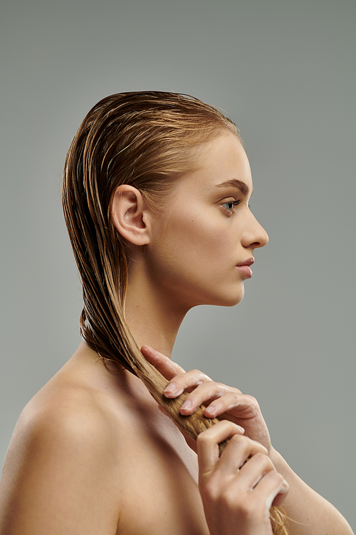 Young woman with long hair tenderly applying hair care products.