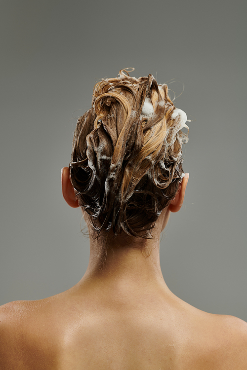 Chic woman applying hair care product and washing hair.