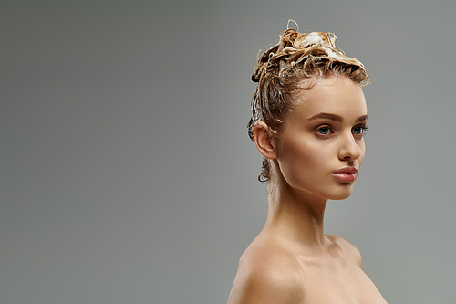 Young woman demonstrates hair care routine with wet hair.