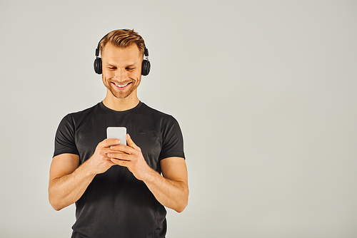 A young man in headphones gazes at his phone screen, absorbed in his digital world.